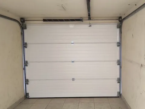 Puerta levadiza seccional con rieles, resortes y herrajes instalados por Automatismos ARPA